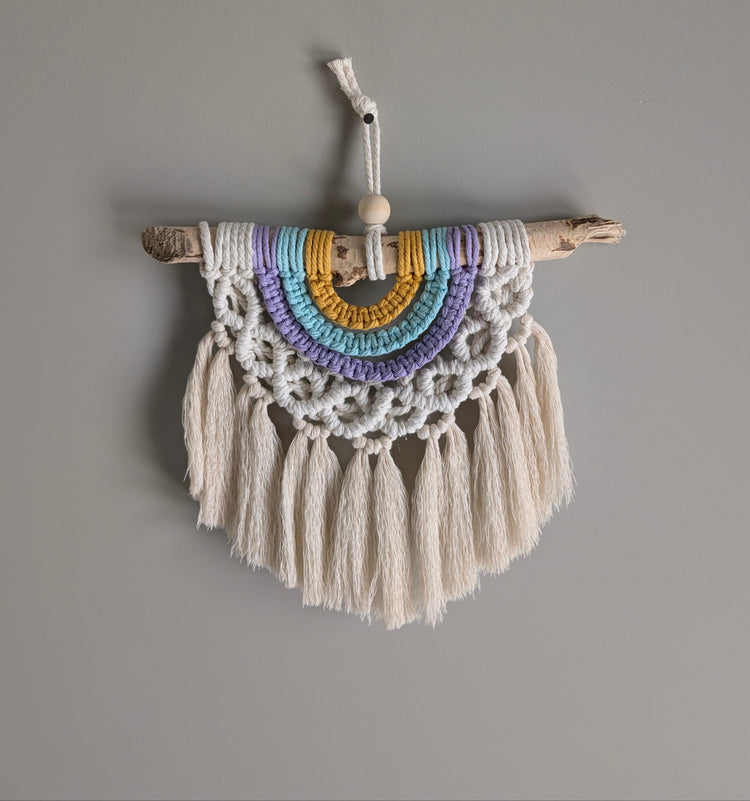 Macrame wall hanging with colorful beads and tassels on a gray background