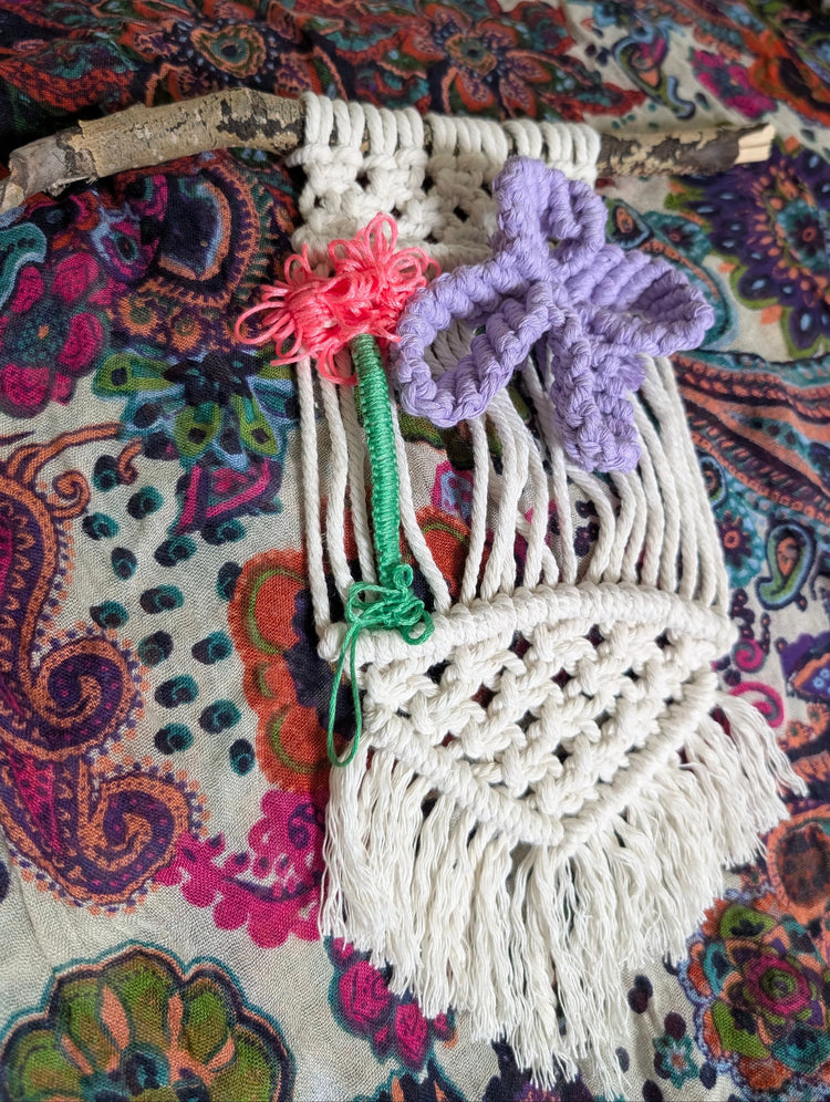 Wall hanging, with a vibran pink flower and green stem and a purple butterfly on a side.