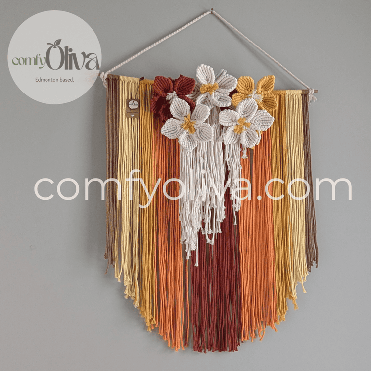 Decorative wall hanging with flowers and ribbons on a gray background, branded 'comfyOliva'.