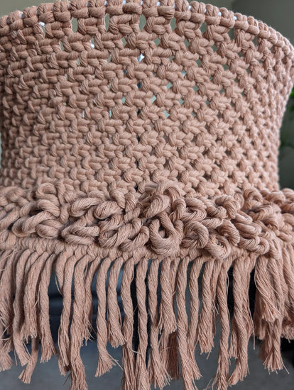 Close-up of a knitted lamp shade with fringes on a dark background