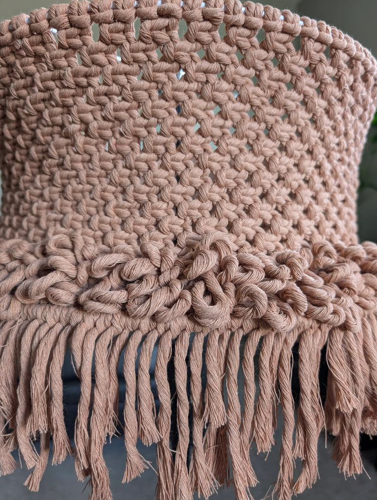 Close-up of a knitted lamp shade with fringes on a dark background