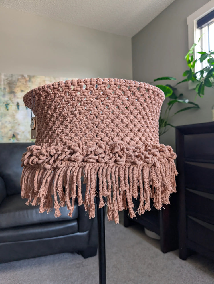 Brown knitted chair cover on a black chair in a room with a plant and furniture.