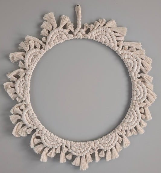 Round macrame wall hanging with tassels on a gray background