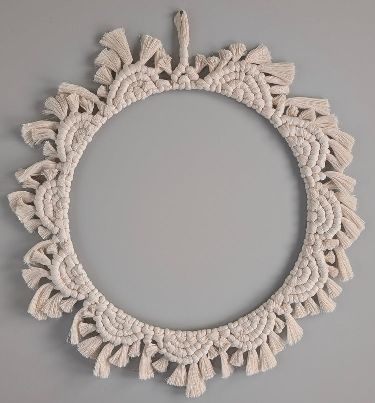 Round macrame wall hanging with tassels on a gray background