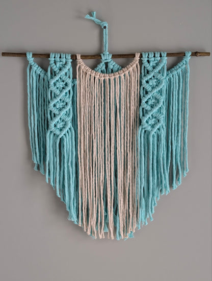 Macrame wall hanging with mint  and beige ropes on a gray background